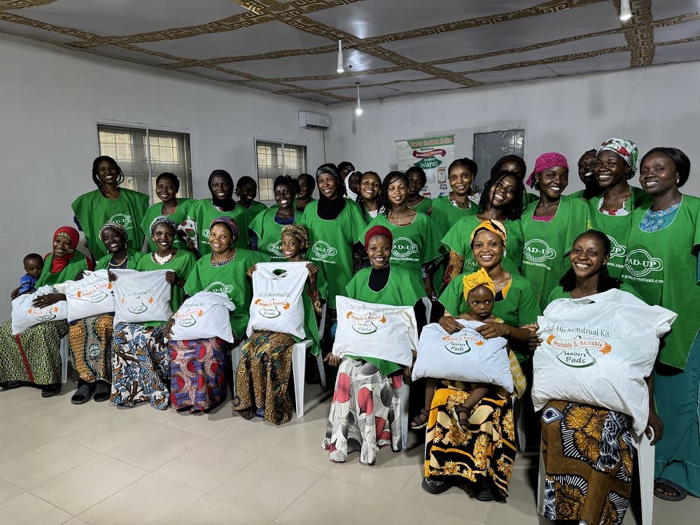 Women in Pad-Up aprons holding menstrual kits after a training session